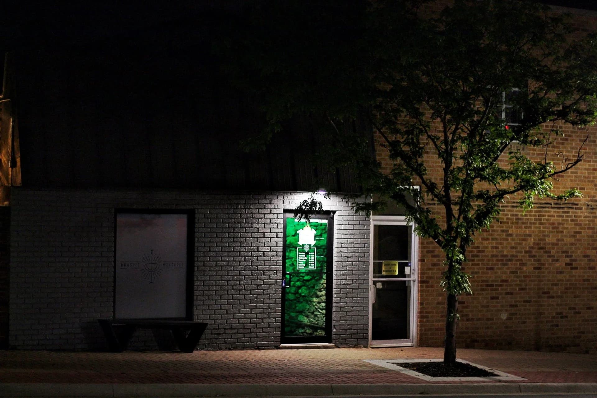The front door of Drastic Measures, lit at night